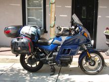 Large, fully-faired touring motorcycle with luggage strapped everywhere.
