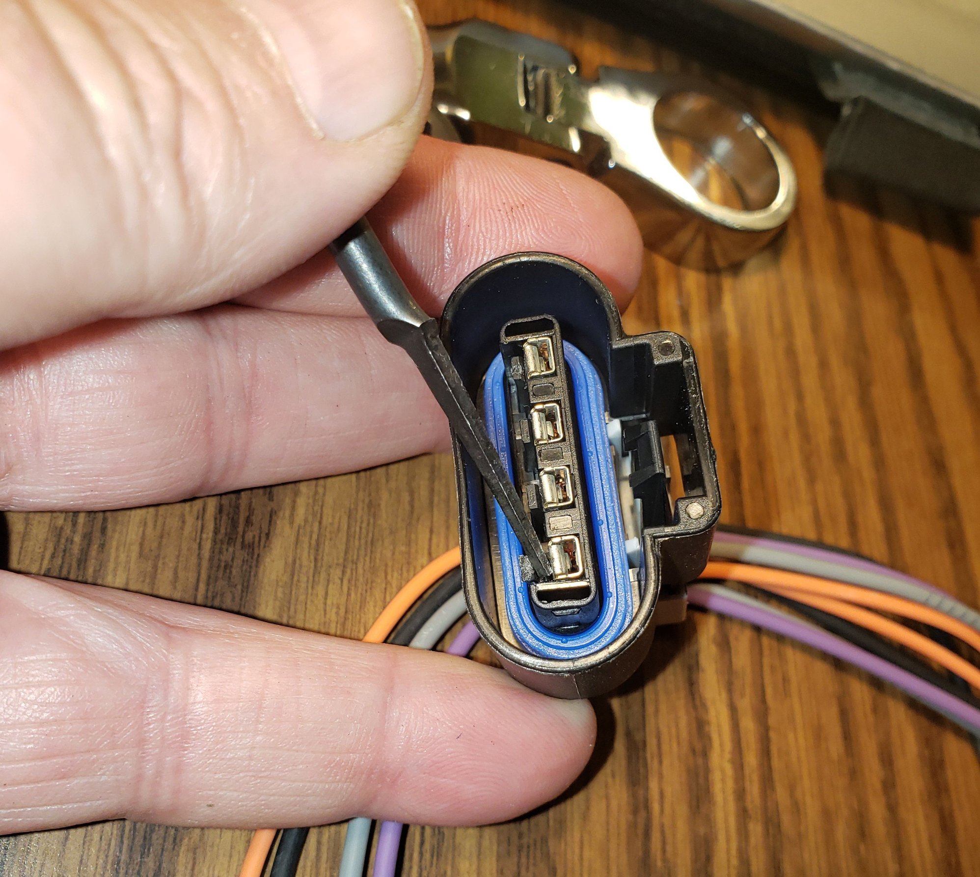 With the blue cap off, the metal connectors are released by pushing down on the retaining clips. The wire is then pull out from the backside.