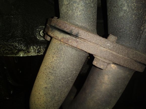 The leak is on the left hand side of the pic. This is looking at the front of the motor with my camera facing the motor just to be clear. You can see a little black soot on the exhaust from the leak. It makes a super annoying ticking sound all the time, and there is black soot on my radiator.