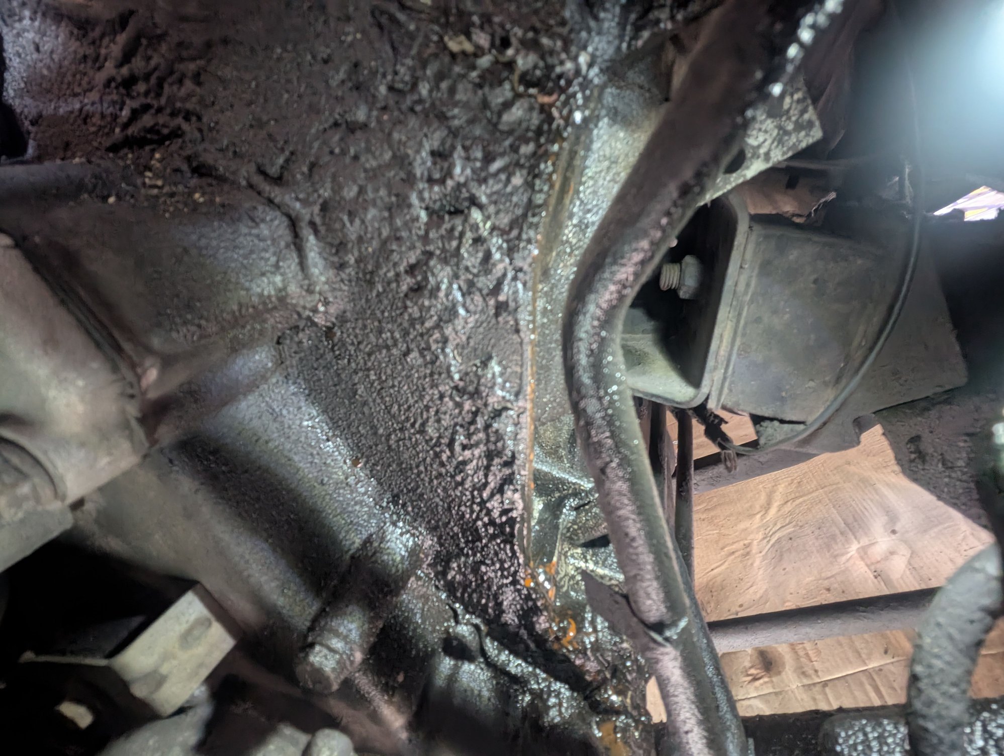 Under the driver side valve cover, quite a way down, coolant. Coolant ends up on the bottom of the transmission pan.