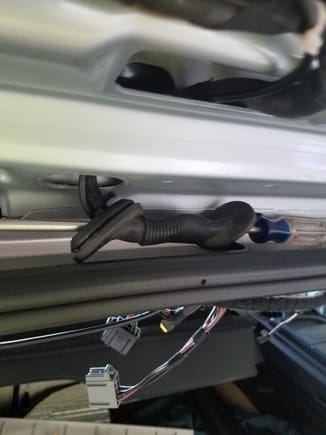 I pushed a screw driver through first to help align the tube in a straight position. I then used a thin wire taped to the cable and pushed it through the tube. This method assures no compromise of the weather seal around the tailgate.