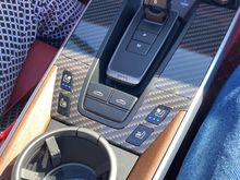 Photo of my $25 upgrade to the panels around the shifter idea of all applying faux carbon fiber self healing film. Took about an hour of time to do this little project by a pro. 

