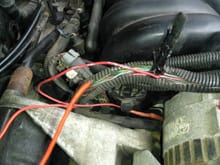 Red Alternator wire spliced to what looks like pink fuel injector wire.  Red wire dangling in forefront comes out of same harness yet is unconnected.