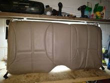 Here is the upper back seat removed from my car. The vinyl/carpet cover is one piece. Once you remove the latching hardware from the seat,