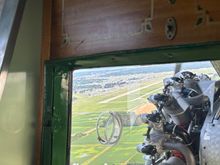 Base leg for runway 36L with the runway visible to the left of the engine 