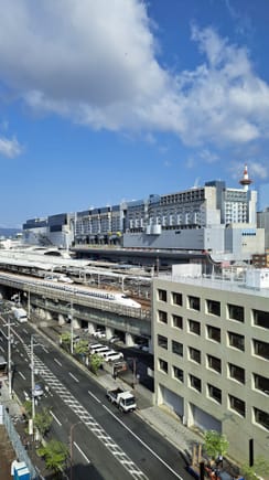 View from the Executive lounge towards the Shinkansen tracks at Kyoto station, with the kyoto station behind it and Kyoto tower  stickig up just at the right edge of the station complex