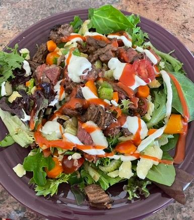 Lunch today - steak salad. Mixed greens, leftover rare grilled skirt steak, extra sharp white cheddar, cherry tomatoes, green onions, green peppers, carrots, celery and a little Ranch/French dressings. 