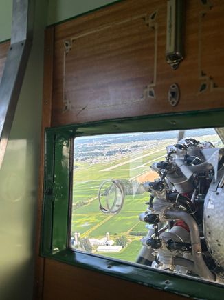 Base leg for runway 36L with the runway visible to the left of the engine 