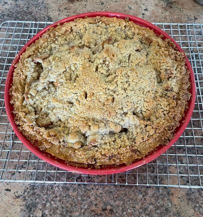 Apple pie with crumb topping cooling on the rack. 