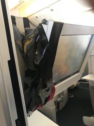 Combination of engineering tape and an infant seat belt being used to hold CW IFE screen in place due to broken hinge mechanism. Unrefurbished LGW 772. CSM told me she always carries a roll of the tape on those aircraft. It sort of worked. 