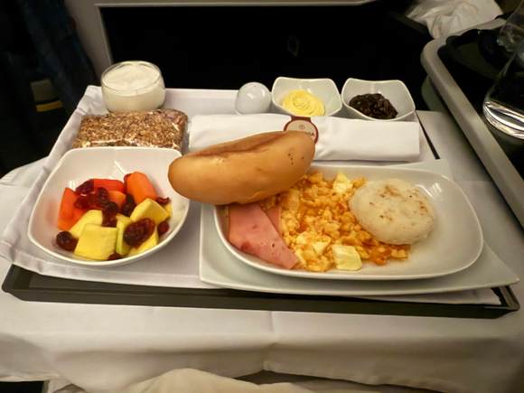 Fruit, a bag of cereal, scrambled eggs, bacon and an arepa