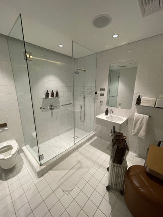 Shower Number 1! After a long day, I decided to shower before the 10 hour flight to LHR. Quantas F lounge shower: Old school tiles, but did the trick. I wish they had a luggage rack, instead of using the ottoman. Space was decent. 