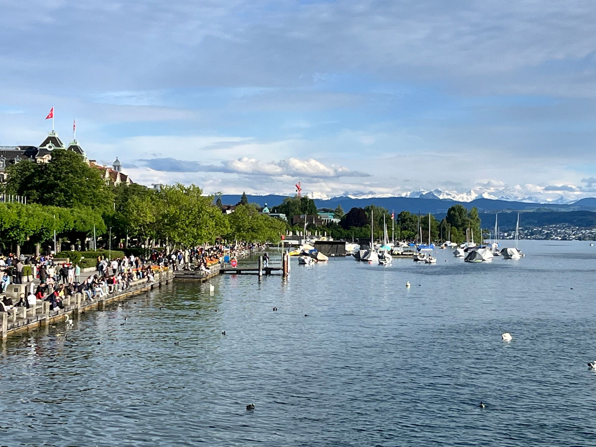 Beautiful Day in Zurich - you can see the snow-capped mountains in the distance. Waterfront is filled with locals