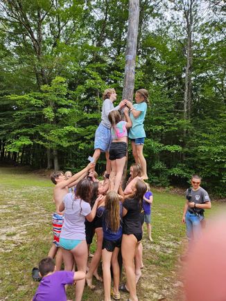 Greased pole climb. Do.lar bills are pasted to the pole with grease. The kids can jump in the river afterwards to get cleaned up. 