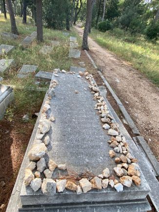 Visitors to the cemetery place stones on a Jewish gravesite as an act of remembrance or respect. 