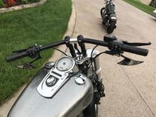 DK custom 2" risers, low profile mirrors, HD grips, black clutch and brake levers, black handlebars, custom silver metallic tank, and front fork lowering springs in this picture