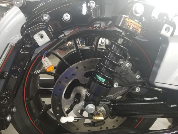 The little white thing near the axle is the air line quick disconnect from the compressor that lives in the saddlebag.  The orange thing is the electrical connector. 