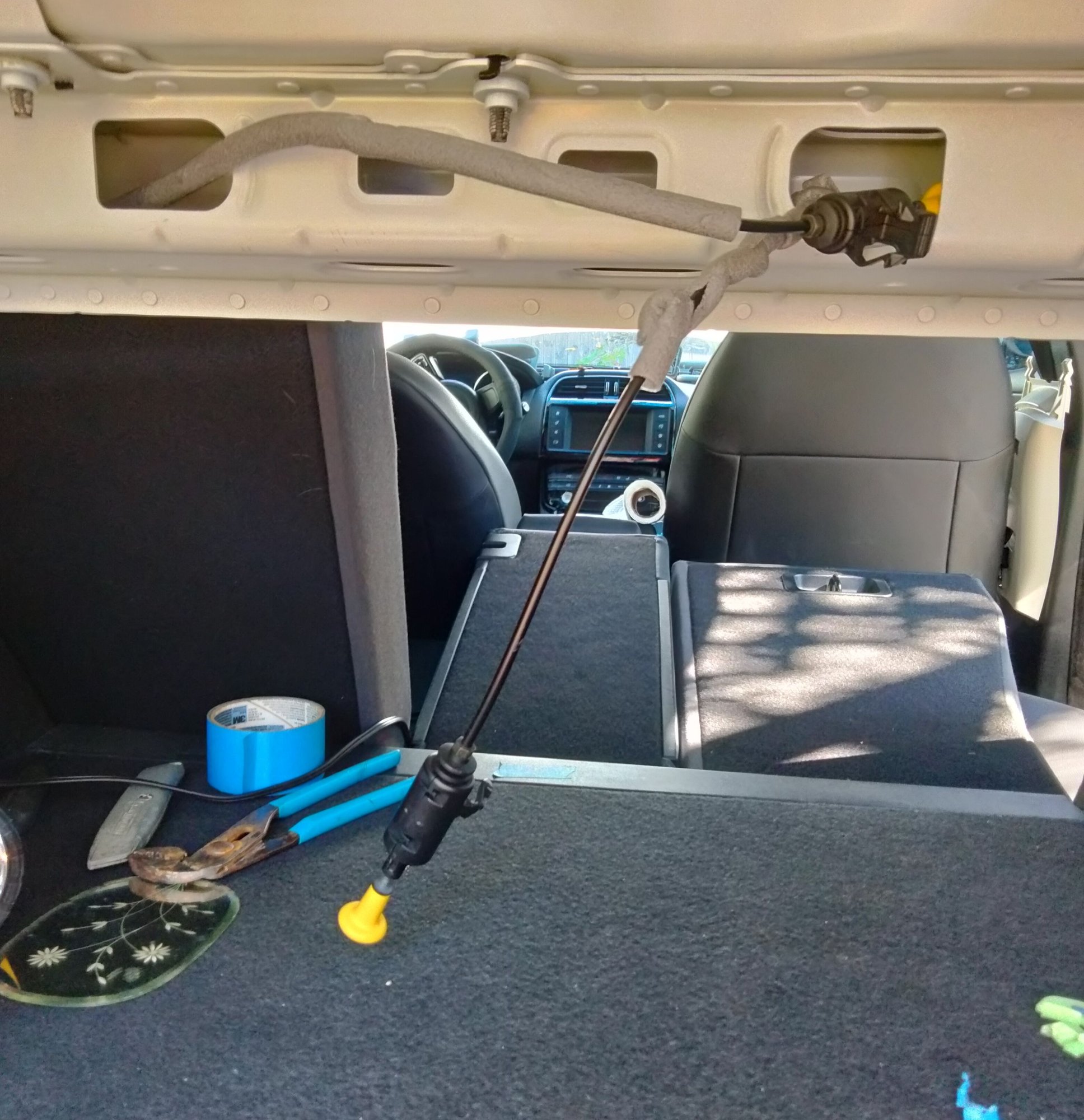 Those two foam-wrapped cables in the upper part of the trunk directly behind the passenger seatbacks release them. Theyre tucked away inside the framing, inside those holes.