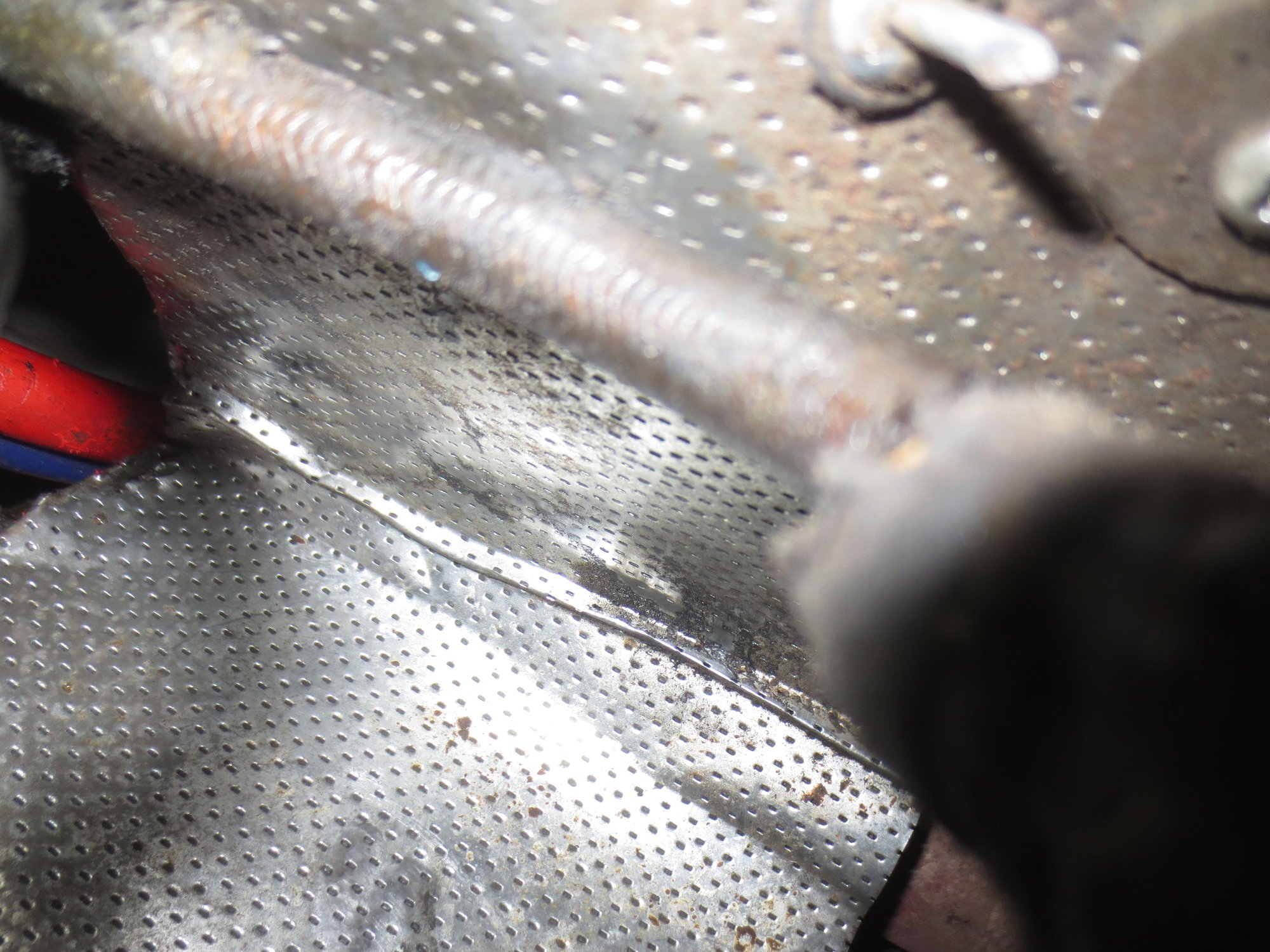 Top of the photo is the outside, bottom shows the arch of heatshield above the starter.
