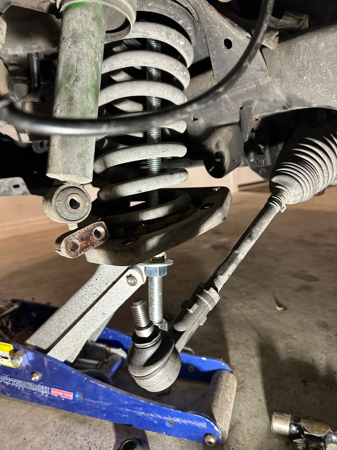 Here's a (so-so) pic of the tool in place within the spring, holding the front part of the lower control arm/plate in place. The jack was 