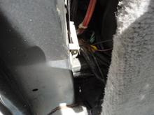 Peeking between the back seat storage locker and with the right rear trim removed. Harness is seen routing to under the rear right quarter window regulator.