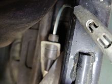 Retaining bracket bottom side. Tangs visible need to be bent back to remove cable.