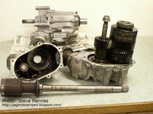 Steve Hannes: The case splits in half to reveal a very simple, two shaft gear design. The shaft assembly to the right is the DRIVE, being fed from the transmission output spline. I'll break it down in a minute. The shaft assembly to the left is the DRIVEN countershaft and is the output to the rear wheels via the driveshaft. There is a bevel gear at the base of the left shaft. It mates with a matching bevel gear (1:1) and makes the 90 degree turn necessary to line up with the driveshaft. 
***** more info: http://jagmotorproject.blogspot.com/2007/02/motor-project-17-transfer-time.html   *****