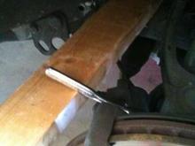 Applying pressure with 2x4 to loosen bolt for rotor removal.