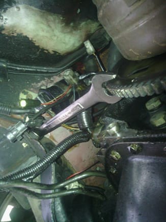 Wrench with the box end secured on a bolt on the chassis, with the spanner wedged in between the teeth on the flexplate to stop it from moving.